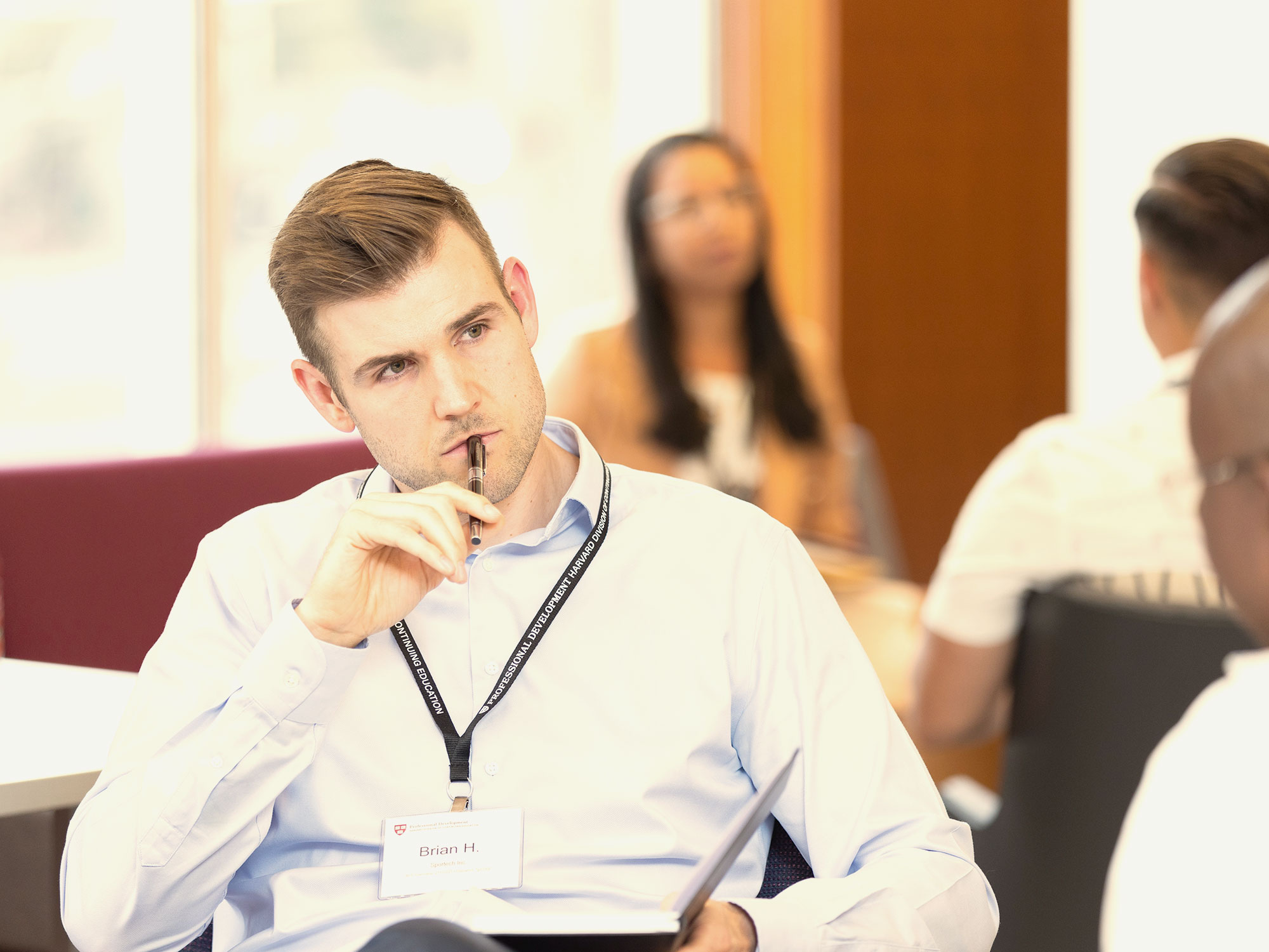 Man in business attire thinking during a group discussion.
