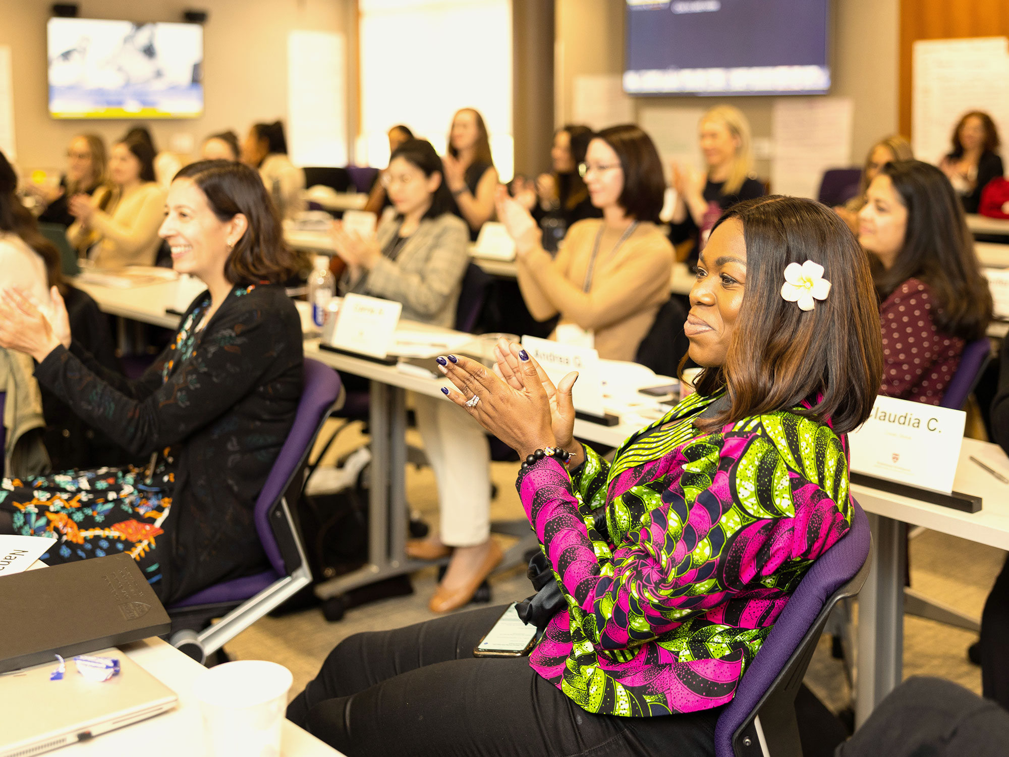 Woman in colorful outfit clapping during a workshop.