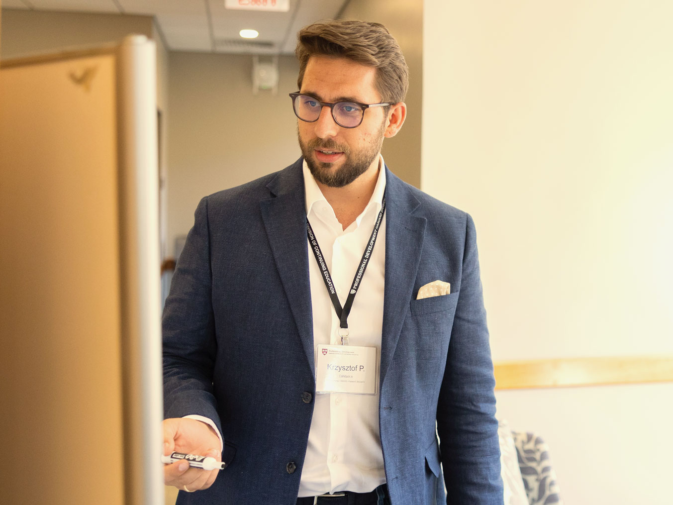 Man in a blue blazer presenting ideas on a whiteboard.