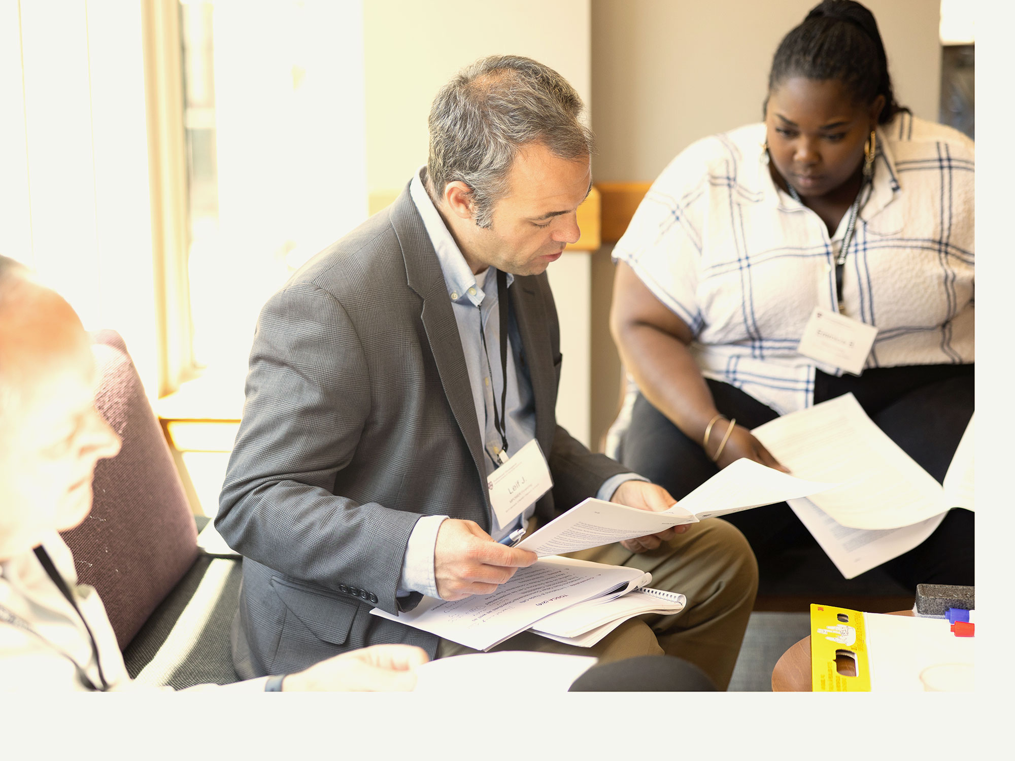 Man reviewing printed documents with teammates during a group exercise.