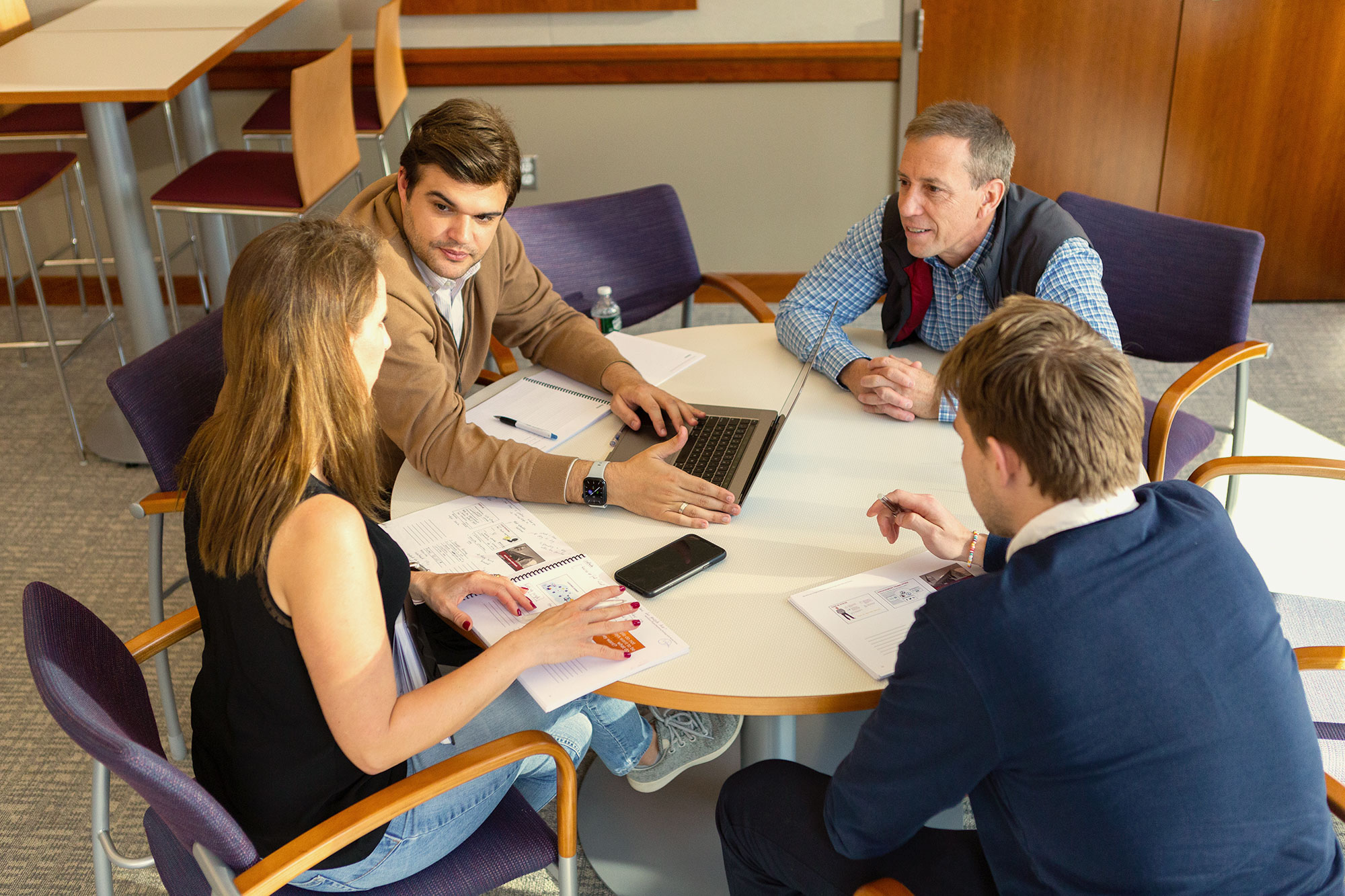 A group of program participants sit around a table doing small group work.