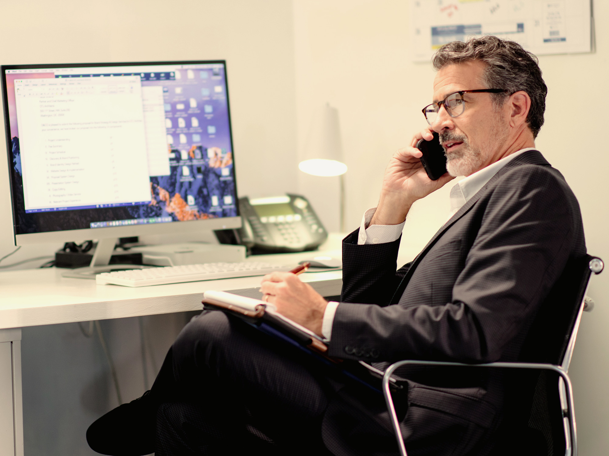man sitting at computer desk on the phone