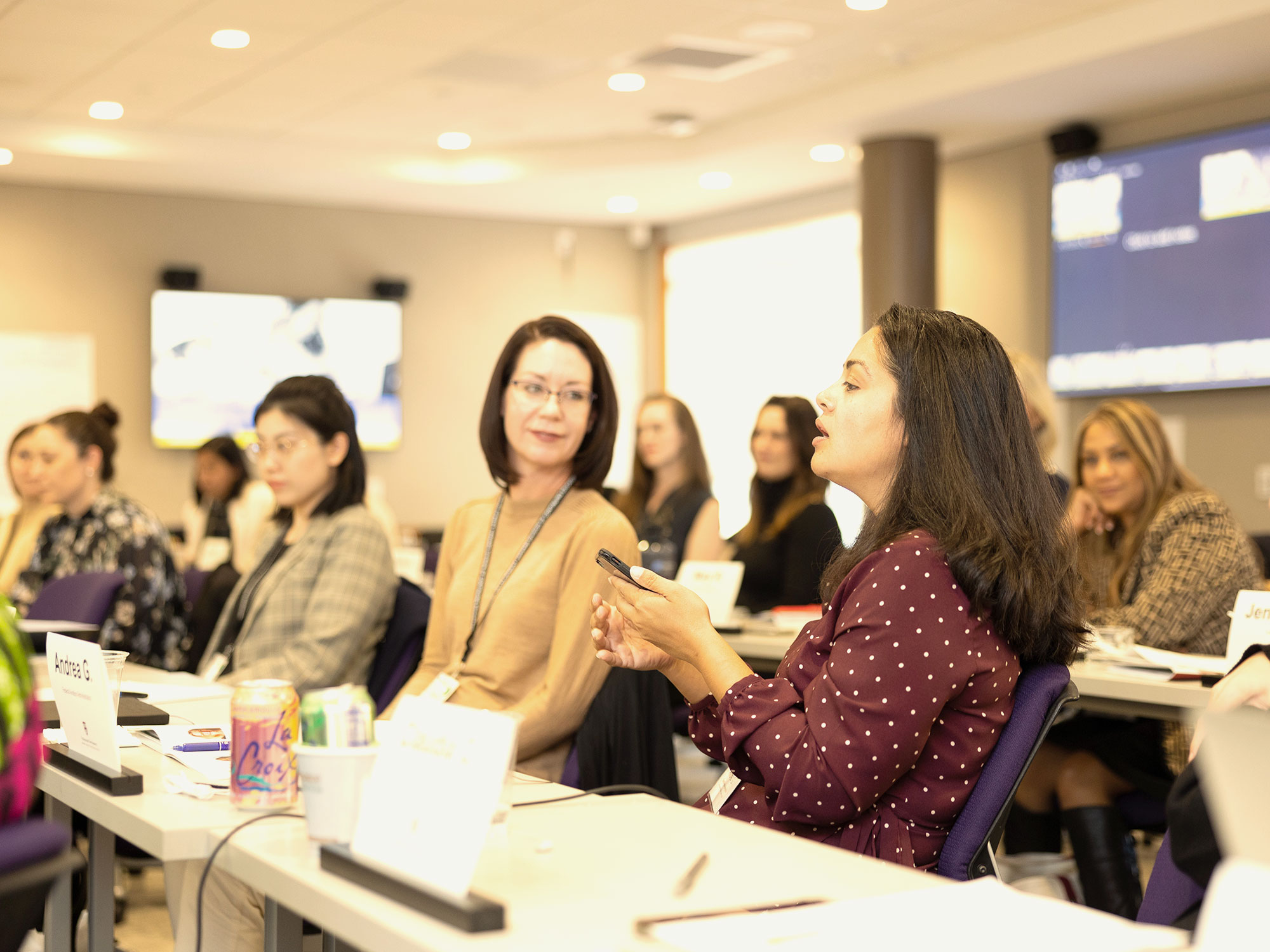 A classroom full of women all looking at a fellow student speaking.