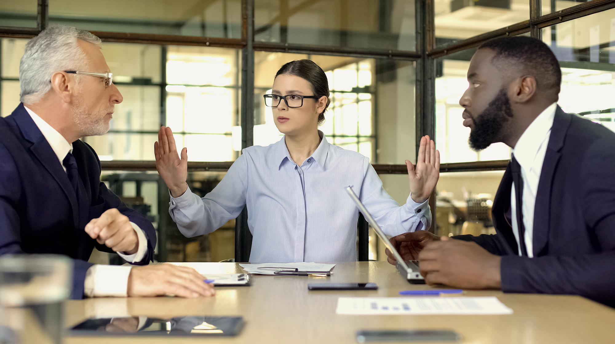 Female manager showing stop sign to arguing workers office, conflict resolution